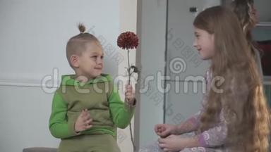 穿绿色睡衣的小男孩给他妹妹<strong>送花</strong>。 家庭关系